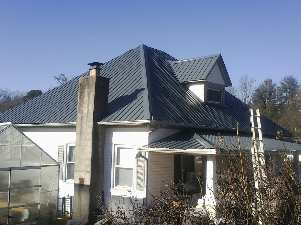 Dark blue standing seam metal roof on a white farmhouse with dormer — Slate & Tile Roof Repair by Roofing Brothers in Allenhurst