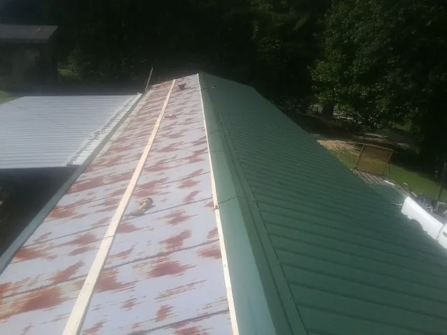 Old rusted panels beside newly installed green metal roofing — Wind Damage Roof Repair by Roofing Brothers in Allenhurst