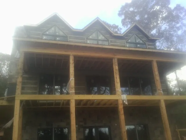 Dormers and porch framing on a large log home under construction — Roof Coating work by our crew in Allenhurst