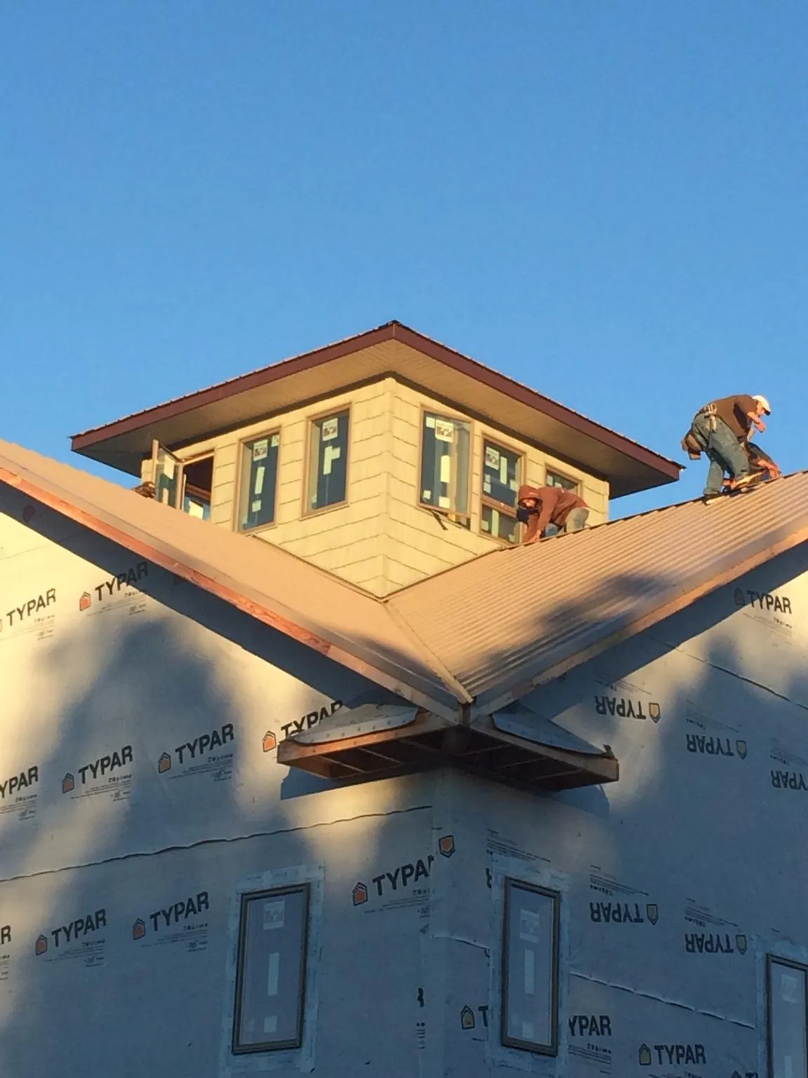 Roofers working around a rooftop cupola on a new metal roof at sunset — Roof Waterproofing in Allenhurst by Roofing Brothers